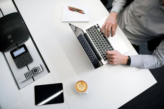 Overhead view of person sitting at a table typing on a keyboard.