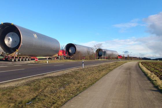 Trucks hauling large cylinders on the highway.